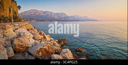 Panoramablick auf die Küste von Kemer mit majestätischen Taurusbergen, die sich am Morgen bei Sonnenaufgang über dem ruhigen Meer erheben. Türkei mittelmeerküste Stockfoto