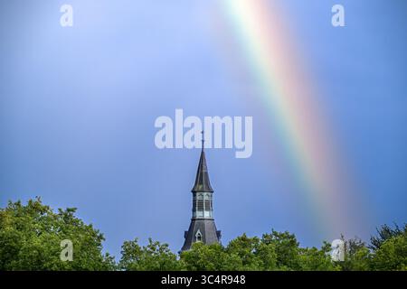 Farbenfroher Regenbogen über Bäumen und Burgturm nach Regenfällen während des Gewitters im Sommer Stockfoto