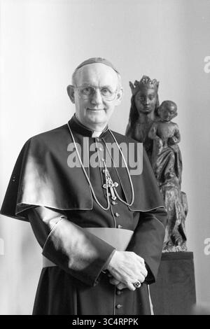 Bischof Bomers, Römisch-Katholische Kirche, 23-02-1989 Whizgle News, Dutch Desk, Niederlande, 1950-2000 Eine angesehene religiöse Figur steht selbstbewusst in traditioneller klerikaler Kleidung, einschließlich eines Gewandes mit Kreuz. Hinter ihm fügt eine dekorative Statue einer Mutter und eines Kindes dem Schauplatz ein spirituelles Element hinzu. Die Atmosphäre vermittelt ein Gefühl von Tradition und Ehrfurcht. Stockfoto
