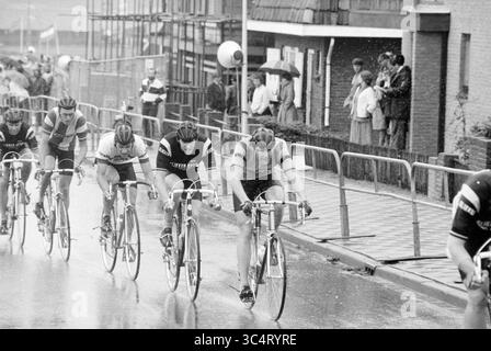 Finish North Holland Cycling Champion, Cycling, 23-05-1981 Whizgle News, Dutch Desk, Niederlande, 1950-2000 Eine Gruppe von Radfahrern tritt an einem regnerischen Tag an einem Rennen an, bei dem das Wasser auf der Straße glitzert. Die Zuschauer beobachten von der Seitenlinie aus, einige von Regenschirmen geschützt, während sich die Radfahrer intensiv auf das bevorstehende Rennen konzentrieren. Stockfoto