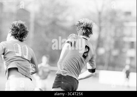 ODIN - de Kennemeren, Football Odin, 06-02-1982 Whizgle News, Dutch Desk, Niederlande, 1950-2000 zwei Fußballspieler befinden sich in einem intensiven Match, wobei ein Spieler ein Trikot Nummer 2 trägt und vor ihm sprintet. Die Bewegung fängt die Energie des Spiels ein, während der andere Spieler, der die Nummer 11 trägt, sich von hinten nähert. Der Hintergrund deutet auf eine geschäftige Feldatmosphäre hin. Stockfoto