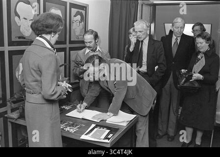 Präsentation des Buches 'Help we are Developed' The Hague Nieuwspoort, Spectrum, 14-03-1978 Whizgle News, Dutch Desk, Niederlande, 1950-2000 Eine Gruppe von Menschen versammelt sich in einem Raum, wobei ein Mann ein Dokument an einem Tisch unterzeichnet. Andere beobachten, einige halten Notizen in der Hand, während eine Frau in der Nähe steht, um sich zu unterhalten. Hinter ihnen sind mehrere gerahmte Porträts an der Wand zu sehen. Stockfoto