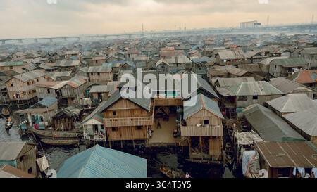 Blick aus der Vogelperspektive auf Holzgebäude mit Wellblechdächern, die dicht über Wasser gepackt sind und ein strukturiertes Mosaik unter einem trüben Himmel bilden, Makoko, Lagos, Nige Stockfoto