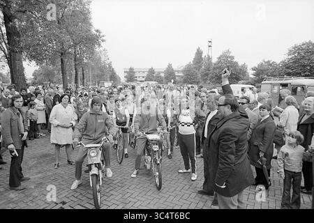 Start Muggeronde, Radfahren, 03-07-1972 Whizgle News, Dutch Desk, Niederlande, 1950-2000 Eine lebhafte Menschenmenge versammelt sich, während sich eine Gruppe junger Motorradfahrer auf ein Event vorbereitet, wobei ein Mann mit Begeisterung im Vordergrund steht. Bäume säumen die Straße, und Besucher jeden Alters beobachten die Szene und schaffen eine lebendige Atmosphäre der Gemeinschaft und Spannung. Stockfoto