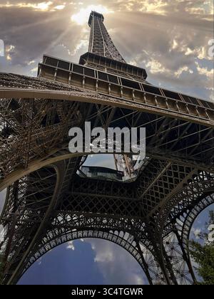 Blick auf den Grund des Eiffelturms, Paris mit Sonnenstrahlen in bedecktem Himmel Stockfoto