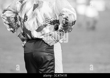 Torhüter RCH, Heemstede, Niederlande, 26-08-1991 Whizgle News, Dutch Desk, Niederlande, 1950-2000 Eine Person steht mit Händen auf der Hüfte, trägt eine farbenfrohe gemusterte Jacke und Torwarthandschuhe und beobachtet ein Spiel im Hintergrund. Stockfoto