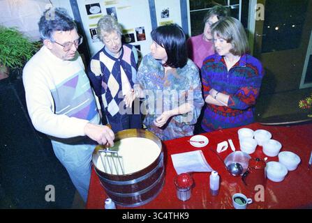 Käserei Zorgvrij, Spaarnwoude, Spaarnwoude, 03-12-1994 Whizgle News, Dutch Desk, Niederlande, 1950-2000 Eine fünfköpfige Gruppe versammelt sich um eine Holzwanne und führt eine lebhafte Diskussion, während ein Individuum eine Mischung mit einem großen Utensilien rührt. Die Atmosphäre ist von Neugier und Zusammenarbeit erfüllt, da sie Tipps und Techniken im Zusammenhang mit der anstehenden Aufgabe austauschen. Verschiedene Küchenartikel sind auf dem Tisch zu sehen, was zur Szene der kulinarischen Teamarbeit beiträgt. Stockfoto