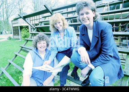 Drei Damen mit Buch MKD Margriet [medizinische Kindertagesstätte], 20-04-1998 Whizgle News, Dutch Desk, Niederlande, 1950-2000 drei Frauen versammeln sich draußen, lächelnd und verwickelt sich in Gespräche. Eine Frau sitzt auf dem Boden, während die anderen neben ihr knien und Dokumente halten. Sie sind von einer natürlichen Umgebung mit Grün und einer architektonischen Kulisse umgeben. Jede Frau hat eine eigene Frisur und trägt legere Kleidung, die eine freundliche und gemeinschaftliche Atmosphäre vermittelt. Stockfoto