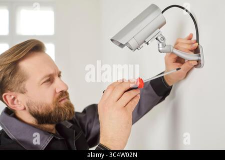 CCTV-Wandinstallation zum Anschließen der kugelförmigen Sicherheitskamera, Mitarbeiter richten das System für die Anzeige ein Stockfoto