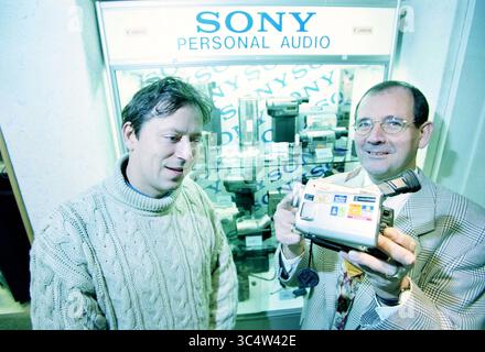 Verschiedene Leute bei Elres, Harlem, Haarlem, Niederlande, 11-11-1998 Whizgle News, Dutch Desk, Niederlande, 1950-2000 zwei Personen stehen vor einem Display mit persönlichen Audiogeräten von Sony, wobei einer einen tragbaren Camcorder zeigt. Die Person, die den Camcorder hält, trägt einen Anzug und Krawatte, während die andere in einem gemütlichen Pullover sitzt, der sowohl engagiert als auch neugierig auf das Produkt wirkt. Stockfoto