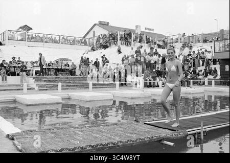 Miss Beach Election Zandvoort II, Zandvoort, Zandvoort, 08-08-1981 Whizgle News, Dutch Desk, Niederlande, 1950-2000 Eine junge Frau läuft selbstbewusst auf einer Plattform am Pool entlang, umgeben von einer hektischen Menschenmenge, die das Geschehen beobachtet. Die Atmosphäre ist energiegeladen, die Zuschauer erwarten den nächsten Moment. Stockfoto