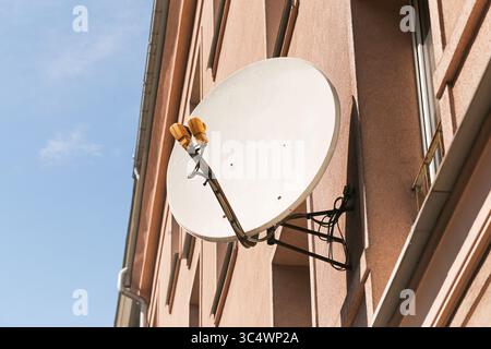 Satellitenschüssel im Gebäude. Kommunikationsempfänger an der Außenwand. Signaltechnologie für städtische Wohngebäude. Antenne für digitale Medien. Stockfoto