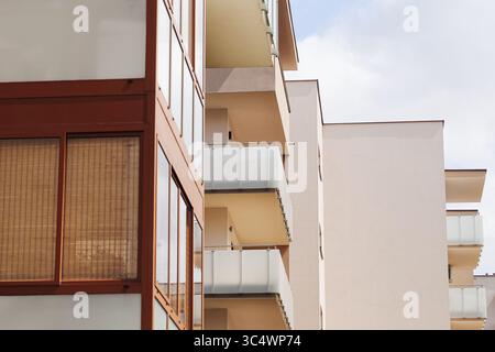 Modernes Wohngebäude. Weiße Fassade mit Balkonen. Städtische Wohnungsentwicklung. Apartmentblock außen. Saubere Architekturlinien. Immobilien. Stockfoto