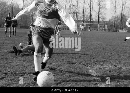 Halfweg - Kennemeren, Football, 10-03-1990 Whizgle News, Dutch Desk, Niederlande, 1950-2000 Ein Fußballspieler in Aktion, der den Ball geschickt über ein grasbewachsenes Feld dribbelt, während Teamkollegen und Gegner im Hintergrund ein intensives Match absolvieren. Die Szene fängt die Energie und Dynamik des Spiels ein. Stockfoto