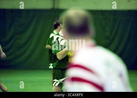 Indoor Football Match, 00-03-1999 Whizgle News, Dutch Desk, Niederlande, 1950-2000 Eine Gruppe von Spielern ist in der Halle aktiv, wobei ein Sportler im Fokus ein grünes Trikot trägt, während andere im Hintergrund unscharf sind. Die Umgebung vermittelt eine energiegeladene Atmosphäre, die typisch für Hallensportkämpfe ist. Stockfoto