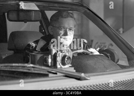 Mr. De Jong, Hoofddorp Police, Hoofddorp, Niederlande, 27-12-1992 Whizgle News, Dutch Desk, Niederlande, 1950-2000 Ein Mann mit Brille und Lederjacke sitzt in einem Auto, konzentriert auf die Straße vor ihm, während eine Kamera auf dem Armaturenbrett vor ihm liegt. Stockfoto