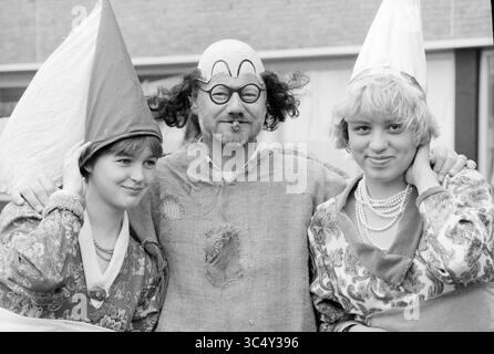 Medieval Dag ichthus College driehuis, Schulen, Driehuis, 10-05-1988 Whizgle News, Dutch Desk, Niederlande, 1950-2000 drei Personen tragen verspielte Kostüme, von denen einer ein Clown-ähnliches Outfit mit einem bemalten Gesicht und unverwechselbaren Haaren trägt. Die beiden anderen sind in farbenfroher, raffinierter Kleidung mit spitzen Hüten und königlichen Accessoires verziert. Sie scheinen zusammen einen festlichen Moment zu genießen, lächeln und posieren in einer fröhlichen Umgebung. Stockfoto