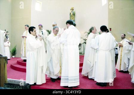 Ordination von vier Diakonen, Heiloo, Heiloo, 24-03-1999 Whizgle News, niederländisches Büro, Niederlande, 1950-2000 Eine Gruppe von Individuen in weißen Gewändern versammelt sich auf einer erhöhten Plattform, die an einem zeremoniellen Ritual teilnimmt. Sie scheinen sich an einem Ort der Anbetung zu befinden, umgeben von religiösen Symbolen, mit Kerzen und Grün, die die Kulisse zieren. Die Atmosphäre vermittelt ein Gefühl von Ehrfurcht und Gemeinschaft. Stockfoto