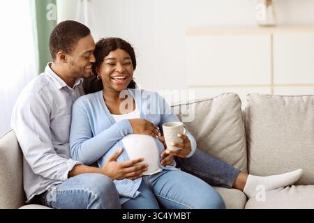 Liebevoller Ehemann küsst seine lachende, schwanger gebliebenes Weib Stockfoto