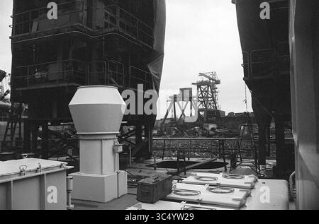 Baukraninsel im Bau in der Gusto Werft in Schiedam, Schiffe, Arbeit, 25-11-1963 Whizgle News, Dutch Desk, Niederlande, 1950-2000 Eine Baustelle mit hoch aufragenden Strukturen und Maschinen, Gerüsten und verschiedenen Ausrüstungen, die über den Boden verteilt sind. Die Szene vermittelt ein Gefühl der industriellen Aktivität und unterstreicht die Komplexität des Standorts und den Prozess des Baus oder der Reparatur großer Schiffe. Stockfoto