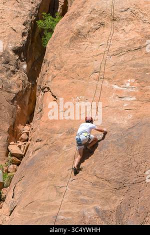Moab, Utah, USA - 25. Mai 2025: Person, die mit Seilen auf einem steilen Felsvorsprung klettert Stockfoto