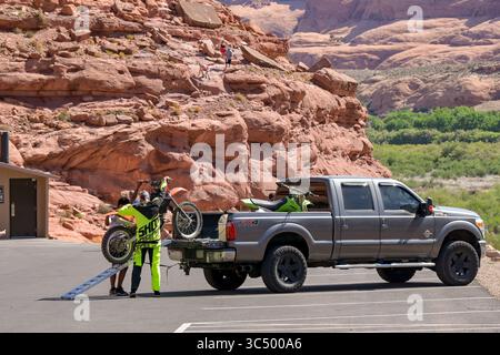 Moab, Utah, USA - 25. Mai 2025: Zwei Personen entladen ein Scrambler-Motorrad von der Rückseite eines Pickup-Trucks Stockfoto