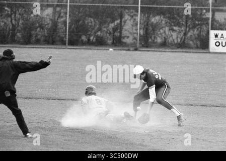 Nicols - Ado, Baseball, 24-05-1975 Whizgle News, Dutch Desk, Niederlande, 1950-2000 Ein Baseballspieler rutscht in die Basis und schleudert eine Wolke aus Staub, während der Gegner versucht, ihn zu markieren. Ein Schiedsrichter signalisiert im Hintergrund und hält einen Moment intensiver Action auf dem Spielfeld fest. Stockfoto