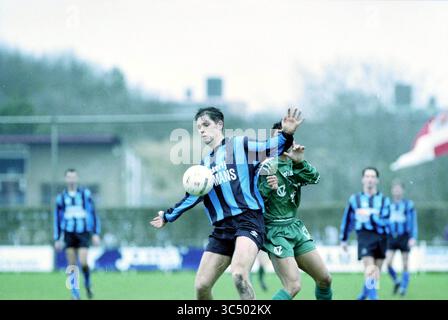 Fußball: Stormvogels - KBV, IJmuiden, IJmuiden, Niederlande, 14-03-1998 Whizgle News, Dutch Desk, Niederlande, 1950-2000 Ein Fußballspieler in einem blau-schwarz gestreiften Trikot kämpft um den Ball und zeigt Entschlossenheit, als er einen gegnerischen Spieler in Grün abwehrt. Im Hintergrund schaffen Teamkollegen und die Atmosphäre eines intensiven Spiels eine lebhafte Szene des Wettkampfgeistes. Stockfoto