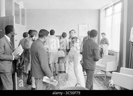 Ausländisches Unternehmen wird begrüßt und gezeigt, 00-04-1967 Whizgle News, Dutch Desk, Niederlande, 1950-2000 Eine Gruppe von elegant gekleideten Personen trifft sich in einem stilvollen Innenraum, einige halten Zeitungen und Zeitschriften. Sie scheinen in Gesprächen zu sein, während andere ihre Umgebung beobachten, mit einem bemerkenswerten Porträt, das an der Wand hängt. Die Atmosphäre deutet auf eine Zusammenkunft oder Veranstaltung hin, die sich auf Diskussion und Interaktion konzentriert. Stockfoto