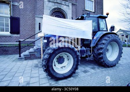 Polder House, Haarlem, Niederlande, 23-11-2000 Whizgle News, Dutch Desk, Niederlande, 1950-2000 Ein blauer Traktor steht vor einem Gebäude, teilweise mit einem weißen Banner bedeckt. Es befindet sich in der Nähe einer Steintreppe, die zum Eingang führt, und die Backsteinfassade des Gebäudes ist im Hintergrund sichtbar. Stockfoto