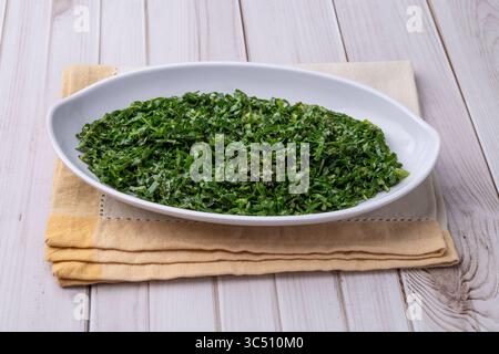 Gekochte Grünkohl-Streifen, typisch brasilianische Feijoada-Beilage in einer Schüssel über einem Holztisch. Stockfoto