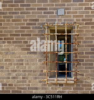 Rostige Sicherheitsriegel um Fenster und Ziegelwand Stockfoto