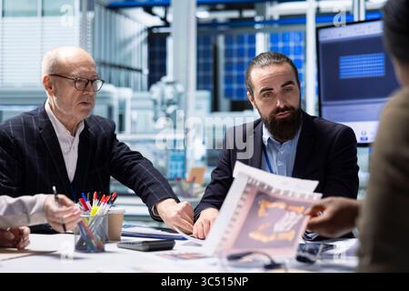 Die Führungskräfte der Photovoltaik-Fabrik sehen sich die Schaltpläne an und planen Arbeiten auf dem Werksgelände. Die Aktionäre von Solarpaneelen sehen sich die Baupläne der Montagelinien an und machen Brainstorming Stockfoto