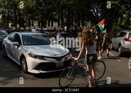 Washington, DC, USA. Juli 2025. Eine Demonstrantin benutzt ihr Fahrrad, um den Verkehr außerhalb der ägyptischen Botschaft in DC zu blockieren, während sie gegen die angebliche Mittäterschaft am anhaltenden Völkermord in Gaza protestiert. (Kreditbild: © Tom Hudson/ZUMA Press Wire) NUR REDAKTIONELLE VERWENDUNG! Nicht für kommerzielle ZWECKE! Quelle: ZUMA Press, Inc./Alamy Live News Stockfoto