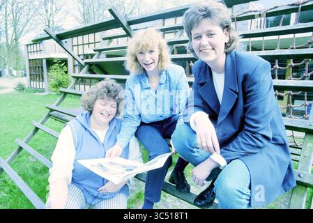 Drei Damen mit Buch MKD Margriet [medizinische Kindertagesstätte], 20-04-1998 Whizgle News, Dutch Desk, Niederlande, 1950-2000 drei Frauen versammeln sich auf einer Reihe von Außentreppen, lächeln und unterhalten sich. Eine Frau hält eine offene Publikation und teilt ihre Inhalte mit den anderen, die sich mit Interesse hineinlehnen. Die Umgebung mit Bäumen im Hintergrund lässt eine angenehme, entspannte Atmosphäre vermuten. Stockfoto