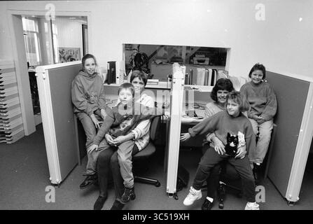 TelePoint, in Verbindung mit Kinderbetreuung Haarlem, Haarlem, Niederlande, 02-11-1992 Whizgle News, Dutch Desk, Niederlande, 1950-2000 Eine Gruppe von sechs Personen, darunter Kinder und Erwachsene, versammelt sich in einem Büro, das an Arbeitsplätzen sitzt, die durch Trennwände getrennt sind. Die Erwachsenen scheinen sich zu unterhalten, während die Kinder spielerisch miteinander interagieren und ein kleines Haustier halten, was eine fröhliche und entspannte Atmosphäre schafft. Stockfoto