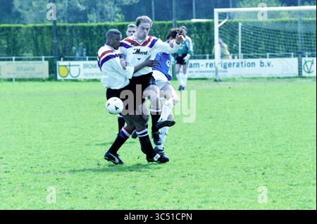 Football, Stormvogels - DCG, IJmuiden, 25-04-1998 Whizgle News, Dutch Desk, Niederlande, 1950-2000 zwei Fußballspieler sind in einem angespannten Moment auf dem Spielfeld um die Kontrolle über den Ball gekämpft. Ein Spieler versucht, den Ball abzuschirmen, während der andere bereit ist, die Intensität des Spiels hervorzuheben. Im Hintergrund wird ein dritter Spieler positioniert, der die Handlung beobachtet. Üppiges Gras bedeckt das Spielfeld, und Werbetafeln sind entlang der Seitenlinie sichtbar. Stockfoto