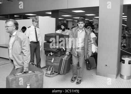 Abflug und Ankunft des 1. Flugzeugs Schiphol, Schiphol, 24-05-1985 Whizgle News, Dutch Desk, Niederlande, 1950-2000 Eine Gruppe von Reisenden navigiert in einem Flughafenterminal, viele mit Gepäck. Ein Mann hebt sich hervor, wenn er mit einem Koffer auf die Kamera zugeht, während andere sich durch den Hintergrund bewegen, einige in Uniform und andere in lässiger Kleidung. Die Szene vermittelt ein Gefühl von Ankunft und Vorfreude in einer belebten Umgebung. Stockfoto