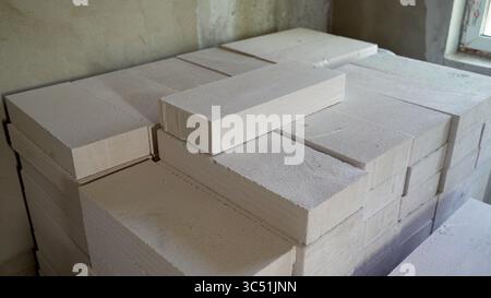 Weiße Porenbetonblöcke, ordentlich gestapelt, einsatzbereit für ein Bauprojekt, was die Vorbereitung und den Beginn der Bauarbeiten bedeutet Stockfoto