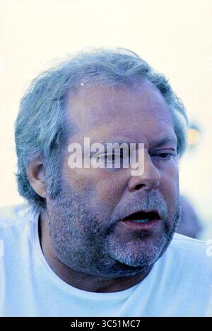 Sommer-Seite: Porträt Oscar Benton, 20-07-1996 Whizgle News, Dutch Desk, Niederlande, 1950-2000 Ein Mann mittleren Alters mit grauen Haaren und Bart scheint tief in Gedanken zu sein oder in Gesprächen verwickelt zu sein, und trägt ein einfaches weißes Hemd. Sein Ausdruck deutet auf einen Moment der Besinnung oder Reflexion hin. Stockfoto