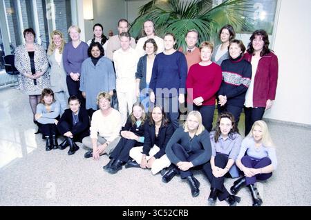 Gruppen Haarlem Zilveren Kruis, Achmea, Haarlem, Niederlande, 08-11-2000 Whizgle News, Dutch Desk, Niederlande, 1950-2000 Eine vielfältige Gruppe von Einzelpersonen posiert zusammen in einem geräumigen Innenbereich und präsentiert eine Mischung aus professioneller und lässiger Kleidung. Sie sind in zwei Reihen angeordnet, einige sitzen auf dem Boden und andere stehen hinter ihnen, alle lächeln und blicken zur Kamera. Eine große Zimmerpflanze verleiht dem Hintergrund einen Hauch von Grün. Stockfoto