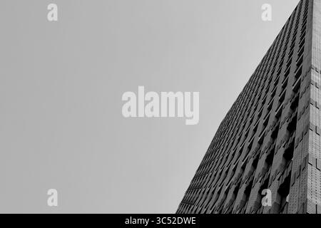 Der monochrome Blick auf den Turm des Symphony Hotels in Amsterdam setzt die gemusterten Fenster mit hellem Himmel in Kontrast und erzeugt ein beeindruckendes Gefühl von Höhe und Geometrie. Stockfoto