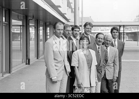 Gruppenfoto, van Vliet, 22-05-1995 Whizgle News, Dutch Desk, Niederlande, 1950-2000 Eine Gruppe von acht Personen steht vor einem modernen Gebäude zusammen und zeigt eine Mischung aus formeller Kleidung. Die Gruppe besteht aus Männern und einer Frau, die alle lächeln und für die Kamera posieren. Ihre Kleidung bietet einen professionellen oder feierlichen Anlass und hebt die Kameradschaft und einen gemeinsamen Moment hervor. Stockfoto