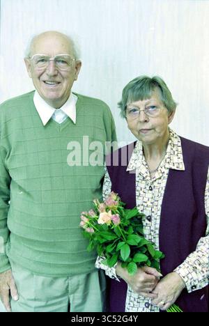 Familienfreund, 50 Jahre alt, Haarlem, Niederlande, 19-09-2001 Whizgle News, Dutch Desk, Niederlande, 1950-2000 ein älteres Paar steht zusammen, mit dem Mann, der einen hellgrünen Pullover über einem weißen Hemd trägt und warm lächelt. Die Frau trägt eine gemusterte Bluse und eine dunkle Weste und trägt einen Strauß rosa Rosen, der ein Gefühl von Zuneigung und Zusammengehörigkeit vermittelt. Stockfoto