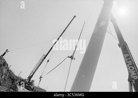 Installation von Rotorblättern auf Windmühle, Waarderpolder, Haarlem, Nederland, 12-06-1989 Whizgle News, Dutch Desk, Niederlande, 1950-2000 Eine Baustelle mit zwei großen Kränen, die zum Heben einer hochaufragenden Struktur positioniert sind, wobei ein Arbeiter den Betrieb vom Boden aus koordiniert. Die Szene erfasst den Umfang und die Komplexität der am Projekt beteiligten Maschinen. Stockfoto