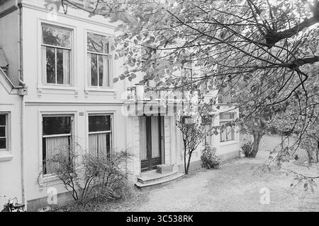 Landsitz Zomerlust, Wagenweg 65, Haarlem, Wagenweg 65, Niederlande, 03-11-1969 Whizgle News, Dutch Desk, Niederlande, 1950-2000 Ein charmantes, historisches Haus mit überdachter Veranda, umgeben von üppigem Grün und Bäumen. Die Fenster sind mit Vorhängen verziert, und der gepflegte Garten lässt eine friedliche, einladende Atmosphäre entstehen. Stockfoto