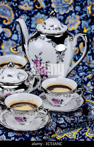 Set aus Vintage-Porzellan-Kaffeetassen auf einem farbenfrohen abstrakten Hintergrund Stockfoto