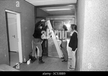 Marinekrankenhaus Squatted, 14-09-1991 Whizgle News, Dutch Desk, Niederlande, 1950-2000 Eine Gruppe von vier Personen arbeitet zusammen, um eine Glastür mit einer Holzdiele zu sichern, die einen Moment der Teamarbeit in einem Flur zeigt. Verschiedene Werkzeuge und Materialien sind sichtbar, was auf ein DIY-Projekt oder eine Renovierung hindeutet. Die Atmosphäre vermittelt ein Gefühl der Dringlichkeit, wenn sie sich auf ihre Aufgabe konzentrieren. Stockfoto