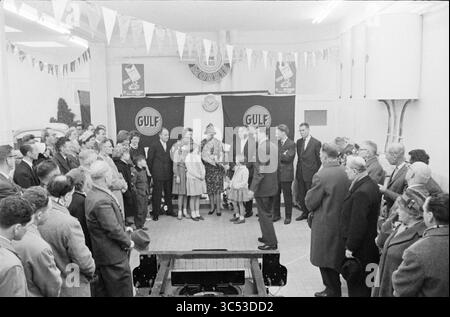 Eröffnung Schmier-/Tankstelle GULF, Brinkmann Haarlem, Eröffnung, Öffnungen, Inbetriebnahme, 26-11-1960 Whizgle News, Dutch Desk, Niederlande, 1950-2000 Eine Zusammenkunft von Menschen in einem geräumigen Raum, der mit Bannern dekoriert ist, die Gespräche führen und Reden hören, während eine Gruppe an der Spitze steht, darunter eine Frau in auffälligem Outfit und ein Kind. Die Atmosphäre strahlt ein Gefühl von Gemeinschaft und Vorfreude aus. Stockfoto
