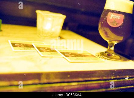 Präsentation Jopenbier, Haarlem, Niederlande, 01-10-2000 Whizgle News, Dutch Desk, Niederlande, 1950-2000 Ein Glas Jopen-Bier steht neben einigen Untersetzern auf einem Tisch und eine sanft leuchtende Kerze sorgt für ein warmes Ambiente. Stockfoto